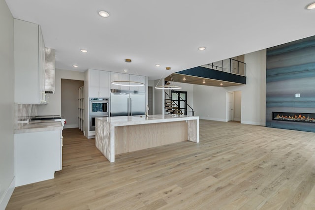 11694 Indian Beach Rd, Spicer, MN 56288 - kitchen with stainless steel appliances, light wood-style flooring, white cabinetry, a center island with sink, and recessed lighting