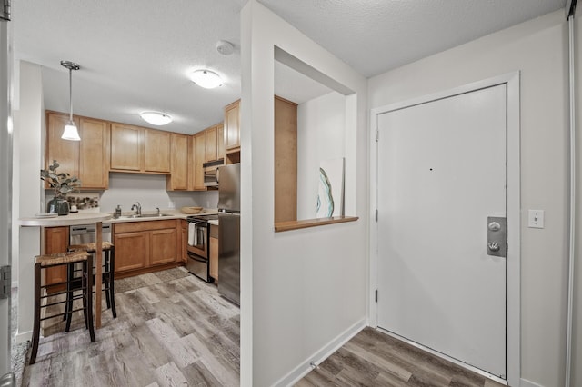 3729 Snelling Ave Unit 203, Minneapolis, MN 55406 - kitchen featuring a textured ceiling, light countertops, a sink, stainless steel appliances, and light wood finished floors