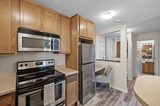 3729 Snelling Ave Unit 203, Minneapolis, MN 55406 - kitchen featuring light wood-type flooring, a textured ceiling, light countertops, stainless steel appliances, and baseboards