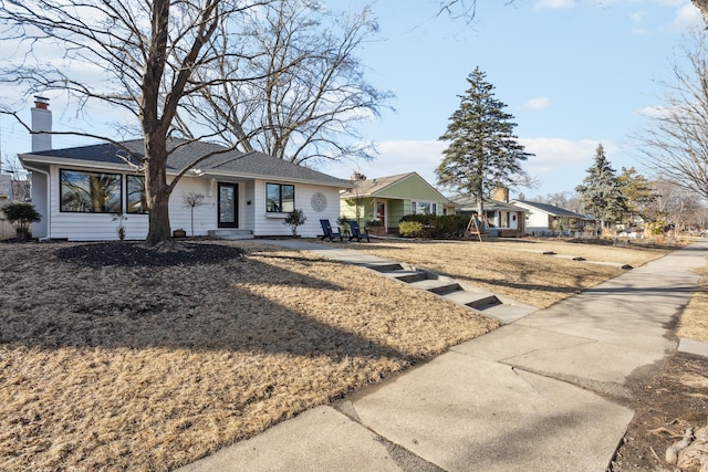 view of front of home with a chimney and roof with shingles
