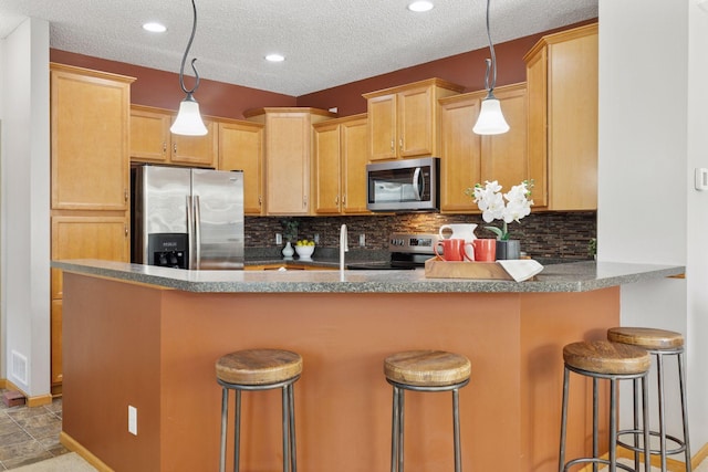 9512 Scott Ln N, Brooklyn Park, MN 55443 - kitchen with appliances with stainless steel finishes, backsplash, a breakfast bar, a peninsula, and recessed lighting