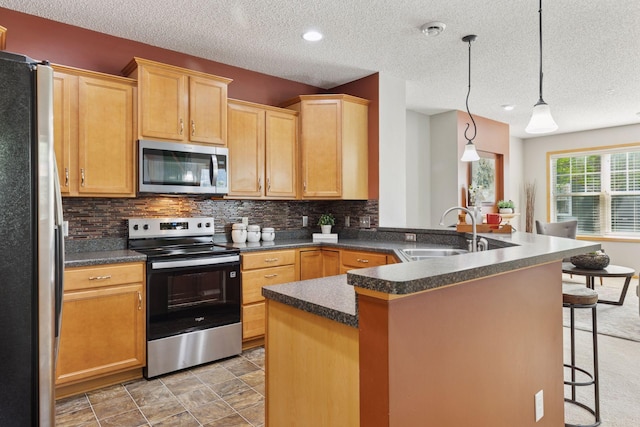 9512 Scott Ln N, Brooklyn Park, MN 55443 - kitchen with appliances with stainless steel finishes, a sink, a kitchen breakfast bar, dark countertops, and decorative backsplash