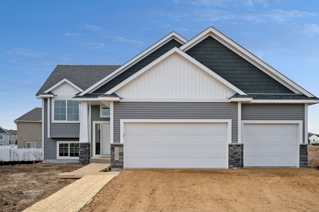 craftsman-style house with board and batten siding, stone siding, and driveway