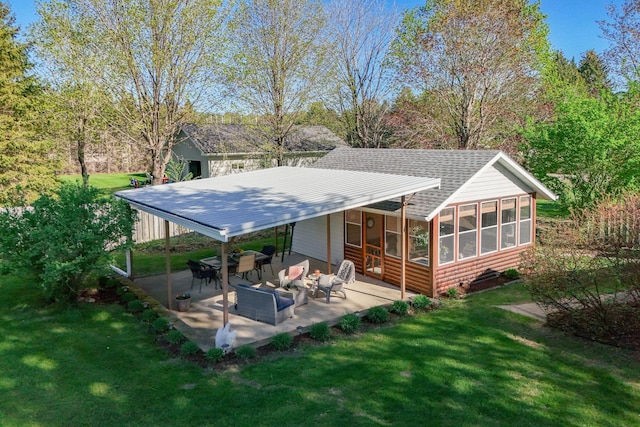 back of property with a sunroom, roof with shingles, a yard, and a patio