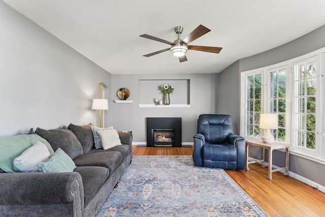 living room featuring healthy amount of natural light, a ceiling fan, baseboards, and wood finished floors