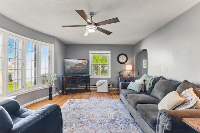 living area with wood finished floors, a ceiling fan, arched walkways, and baseboards