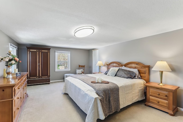 bedroom featuring light carpet, baseboards, and a textured ceiling