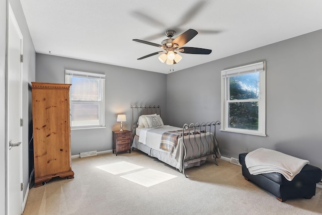 carpeted bedroom featuring multiple windows, baseboards, and a ceiling fan