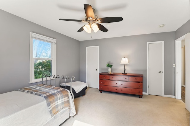 bedroom featuring light carpet, a ceiling fan, and baseboards