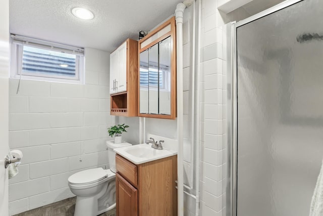 full bathroom featuring a shower stall, a textured ceiling, toilet, and vanity