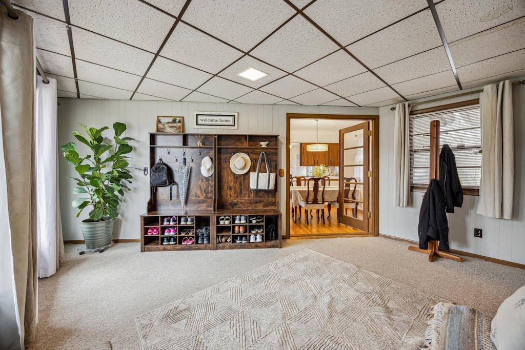 interior space featuring a paneled ceiling, baseboards, and carpet