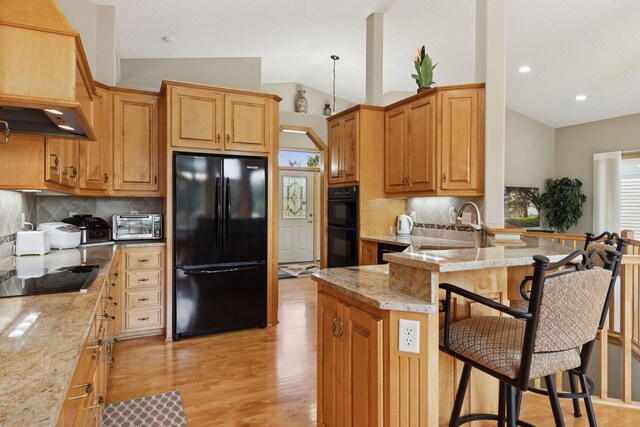 11871 Flanders Cir NE, Blaine, MN 55449 - kitchen with black appliances, vaulted ceiling, a kitchen breakfast bar, tasteful backsplash, and light wood-style floors