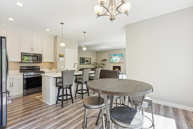 3344 26th Ave S, Saint Cloud, MN 56301 - dining room featuring light wood-style flooring, recessed lighting, a chandelier, a warm lit fireplace, and baseboards