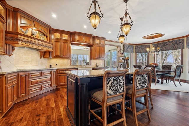 kitchen with a kitchen island, light stone counters, a notable chandelier, glass insert cabinets, and dark wood-type flooring