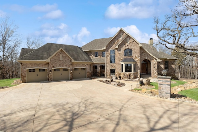 french country home featuring a chimney, a garage, concrete driveway, a shingled roof, and stone siding