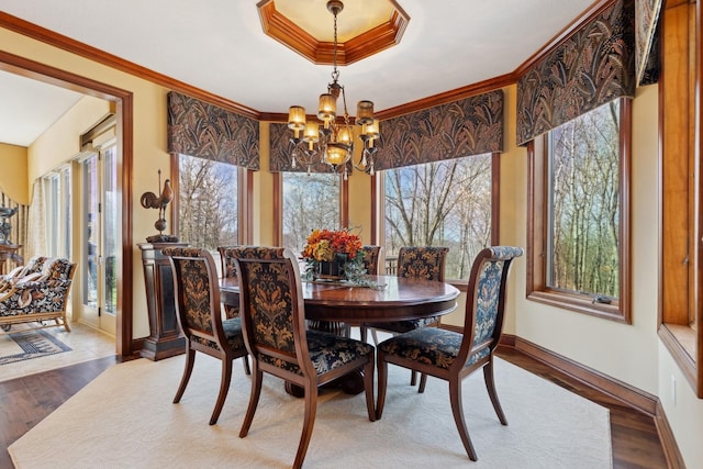 dining space with an inviting chandelier, baseboards, crown molding, and wood finished floors