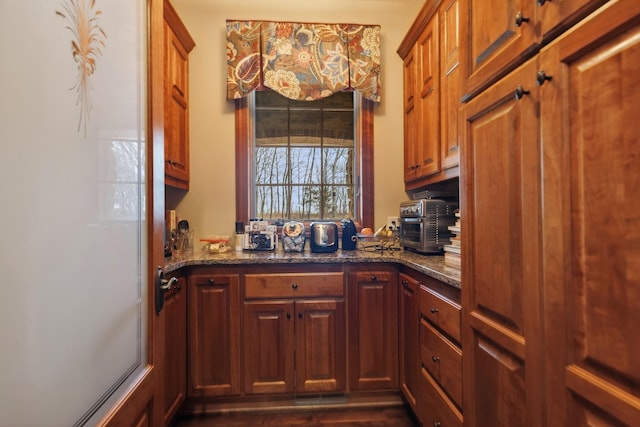 kitchen featuring dark stone counters, a toaster, and dark wood-type flooring