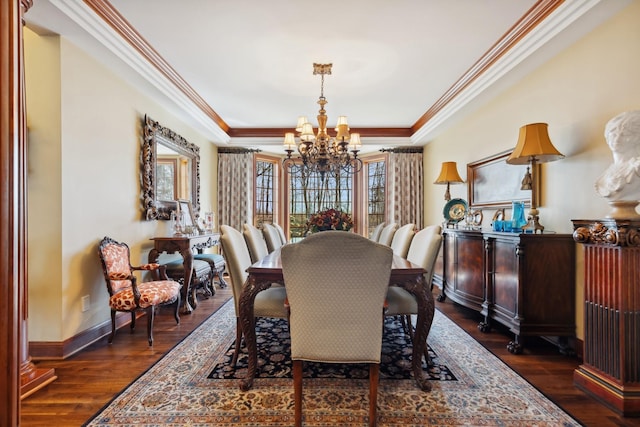 dining area featuring dark wood-style flooring, a chandelier, baseboards, a tray ceiling, and ornamental molding