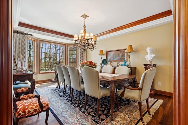dining space featuring crown molding, baseboards, an inviting chandelier, and wood finished floors