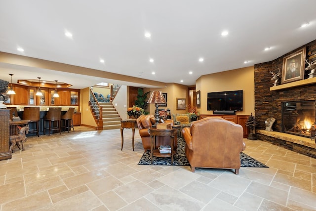 living room with a fireplace, stone tile floors, recessed lighting, indoor bar, and stairway