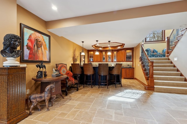 bar with hanging light fixtures, tasteful backsplash, stairs, recessed lighting, and stone tile floors