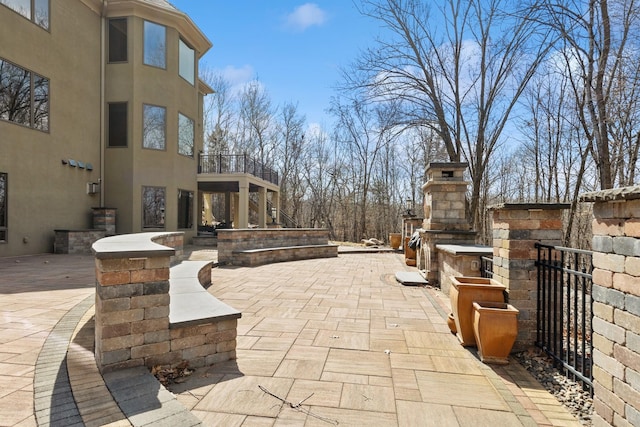 view of patio with an outdoor fireplace and a balcony