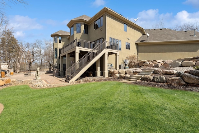 back of property with a lawn, stairs, a patio area, and stucco siding