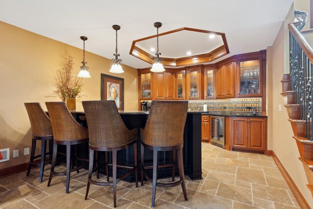 17620 Xanadu Ave, Jordan, MN 55352 - indoor wet bar with a tray ceiling, wine cooler, tasteful backsplash, stone tile floors, and hanging light fixtures