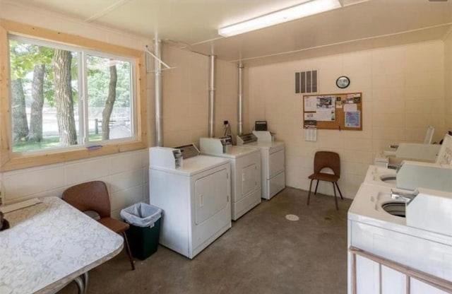 community laundry room featuring independent washer and dryer, visible vents, and tile walls