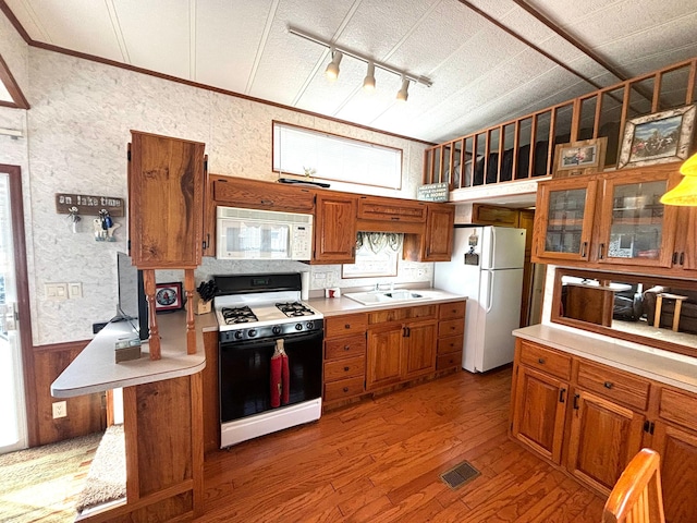 kitchen with white appliances, light countertops, a sink, and brown cabinetry
