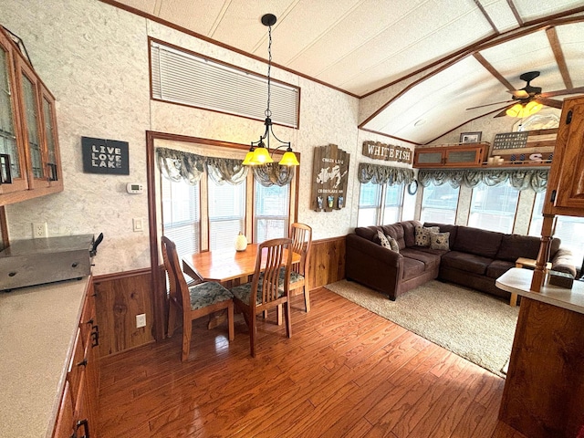 dining space with ceiling fan, wooden walls, wainscoting, and wood-type flooring