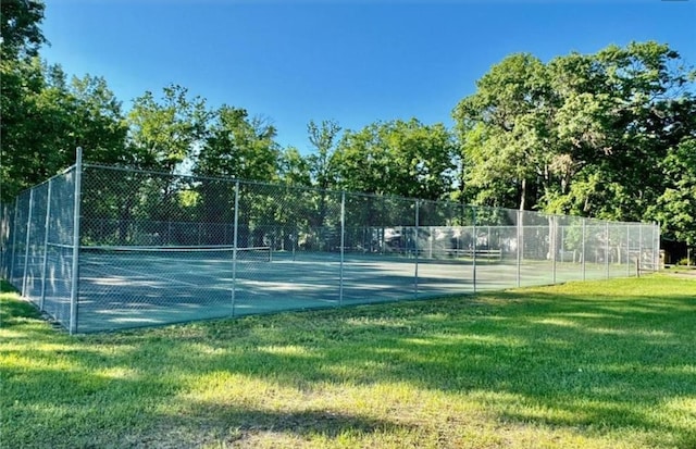 view of sport court featuring fence and a yard