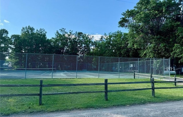 view of tennis court featuring a yard and fence