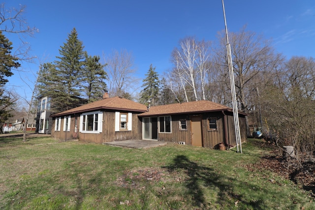 rear view of property with a yard, a chimney, and a patio area