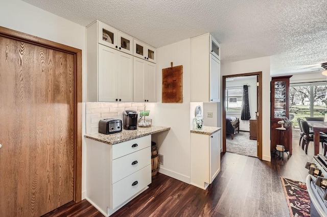kitchen with white cabinetry, dark wood finished floors, and glass insert cabinets
