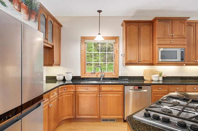 6507 Orchard Ridge Trl, Woodbury, MN 55129 - kitchen featuring stainless steel appliances, decorative light fixtures, dark stone countertops, glass insert cabinets, and brown cabinets