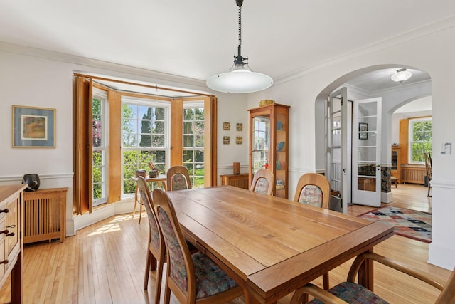 2924 Farwell Ave, Minneapolis, MN 55411 - dining space with arched walkways, french doors, radiator heating unit, light wood-style flooring, and crown molding