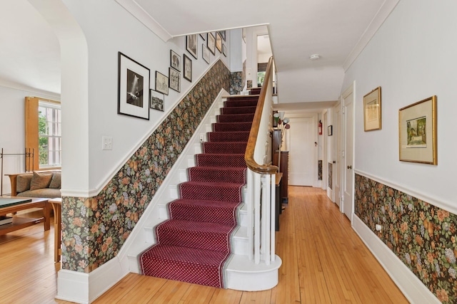 2924 Farwell Ave, Minneapolis, MN 55411 - stairway featuring wallpapered walls, hardwood / wood-style flooring, crown molding, and arched walkways