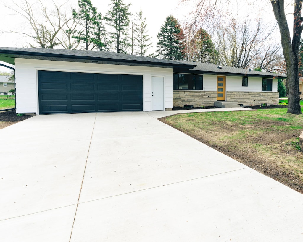view of front of property with driveway, stone siding, and a garage