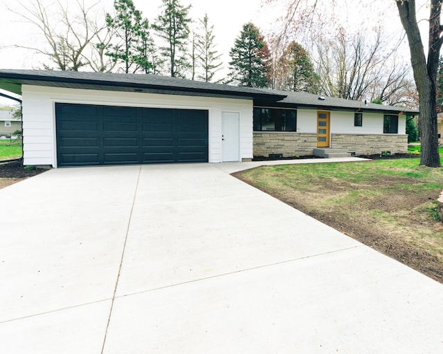 view of front of property with driveway, stone siding, and a garage
