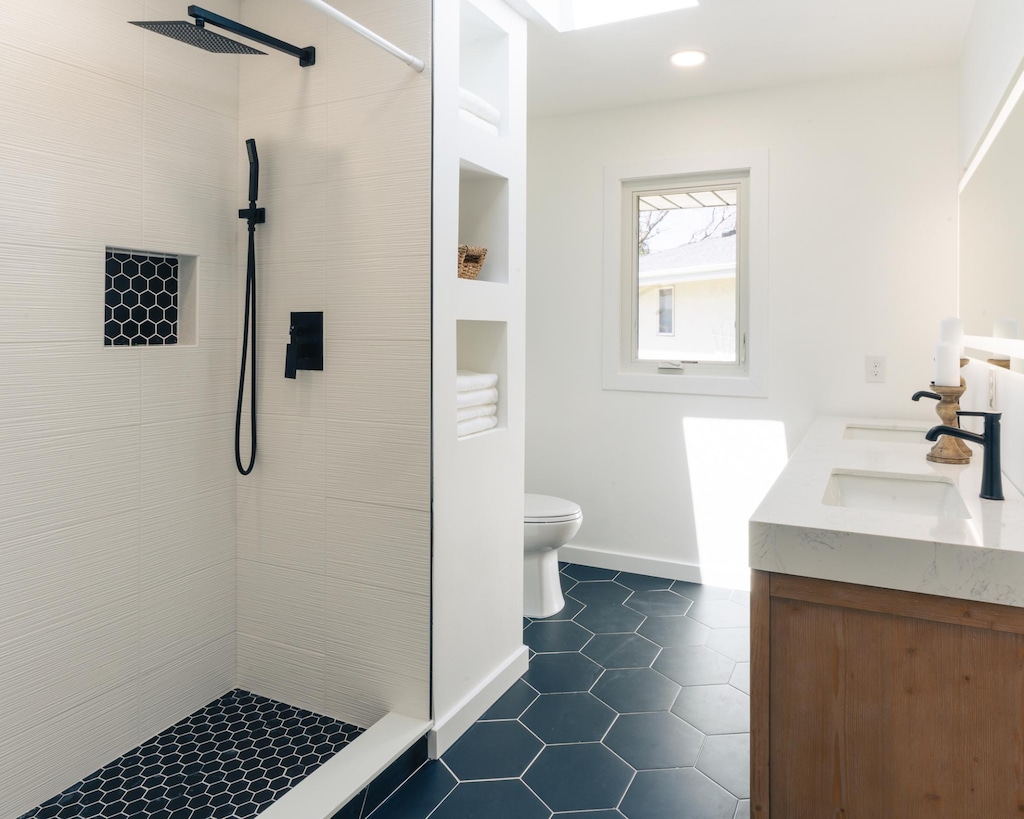 bathroom featuring tile patterned flooring, double vanity, toilet, recessed lighting, and tiled shower