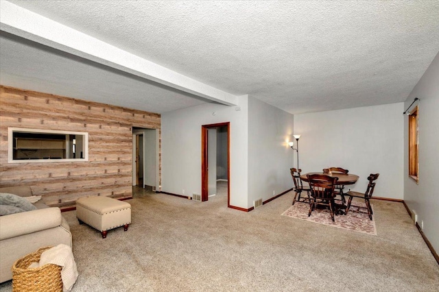 carpeted living room with wood walls, baseboards, and a textured ceiling