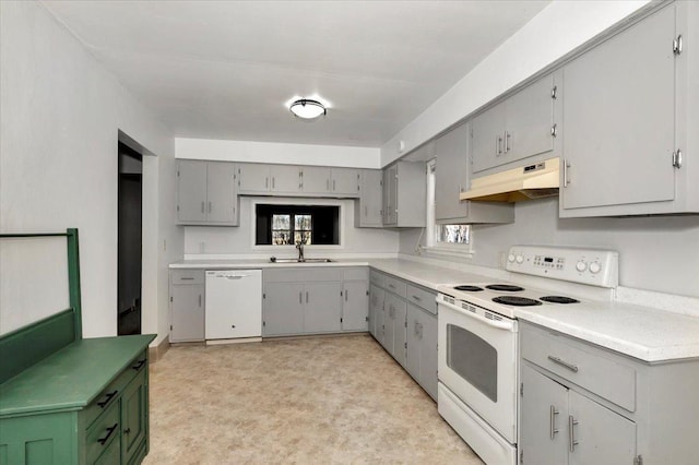 kitchen featuring white appliances, under cabinet range hood, a sink, and gray cabinetry