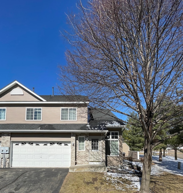 view of front of house with brick siding, driveway, a garage, and roof with shingles