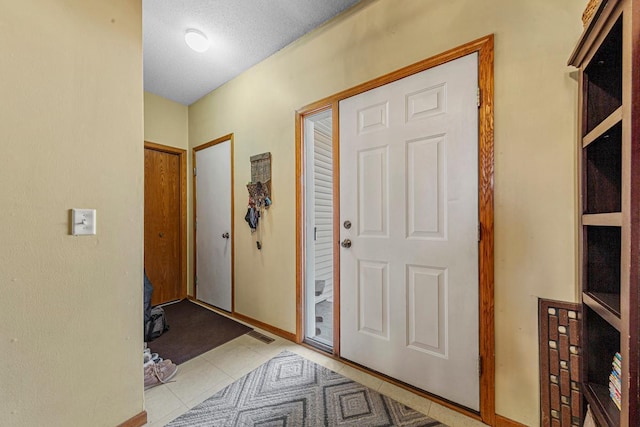 foyer with light tile patterned floors and a textured ceiling