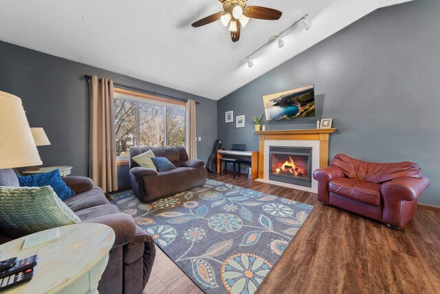living area with track lighting, a fireplace, wood finished floors, ceiling fan, and lofted ceiling