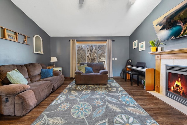 living area featuring vaulted ceiling, a tiled fireplace, and wood finished floors