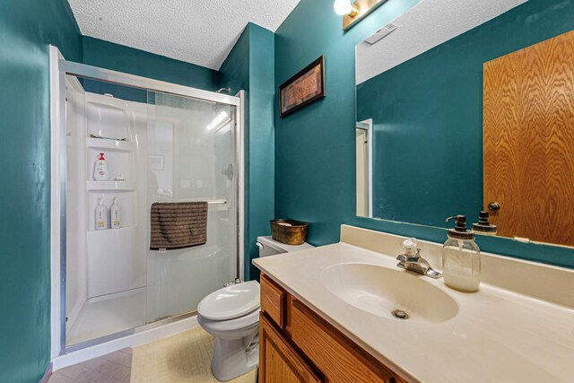 full bath with toilet, vanity, a textured ceiling, and a shower stall
