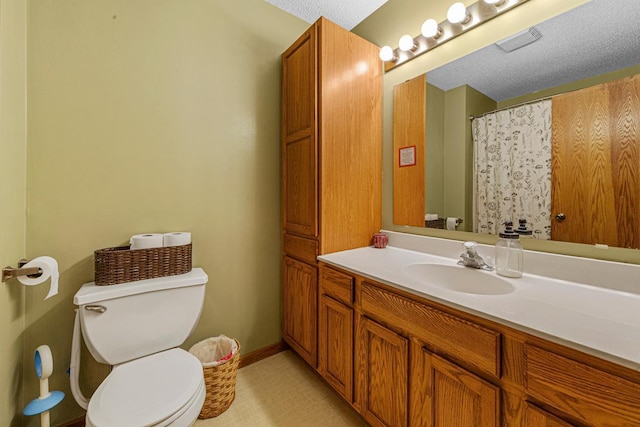 full bath featuring toilet, vanity, a textured ceiling, baseboards, and visible vents