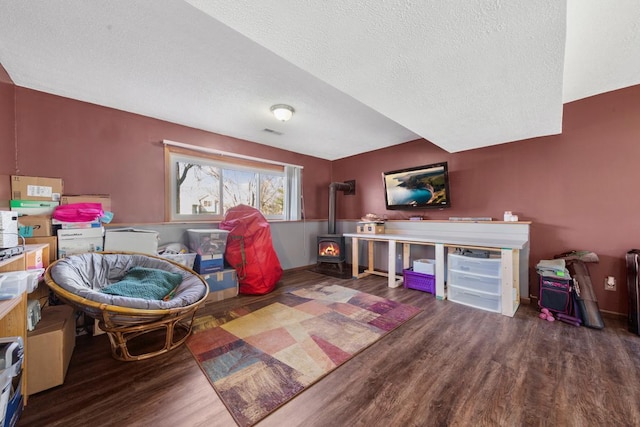 recreation room featuring visible vents, wood finished floors, a wood stove, and a textured ceiling